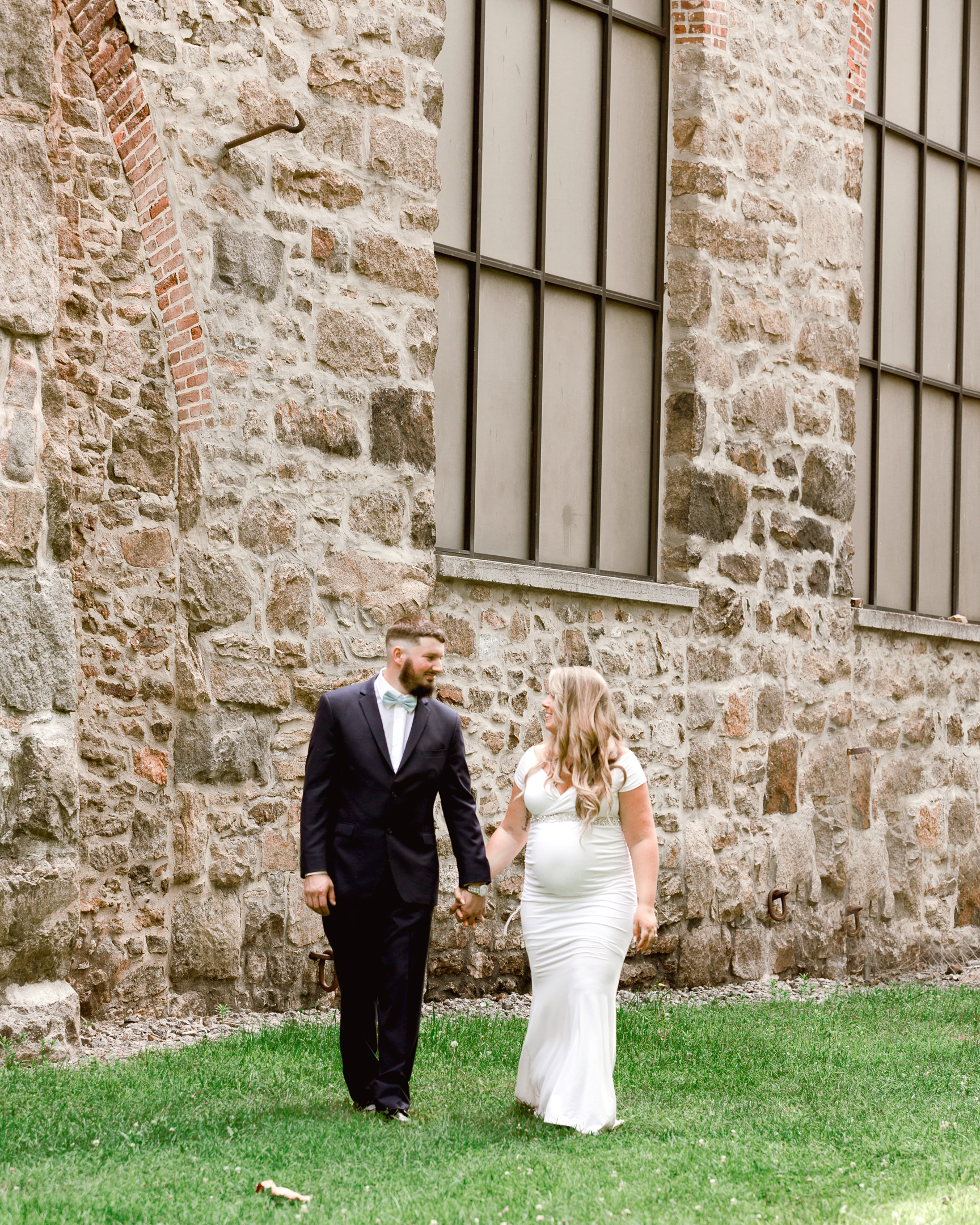 Bride and groom walking in front of a large stone building